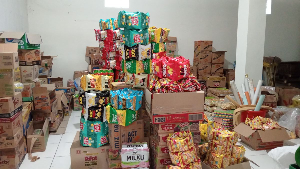 Tumpukan mie instan, snack, dan kardus sembako di gudang toko