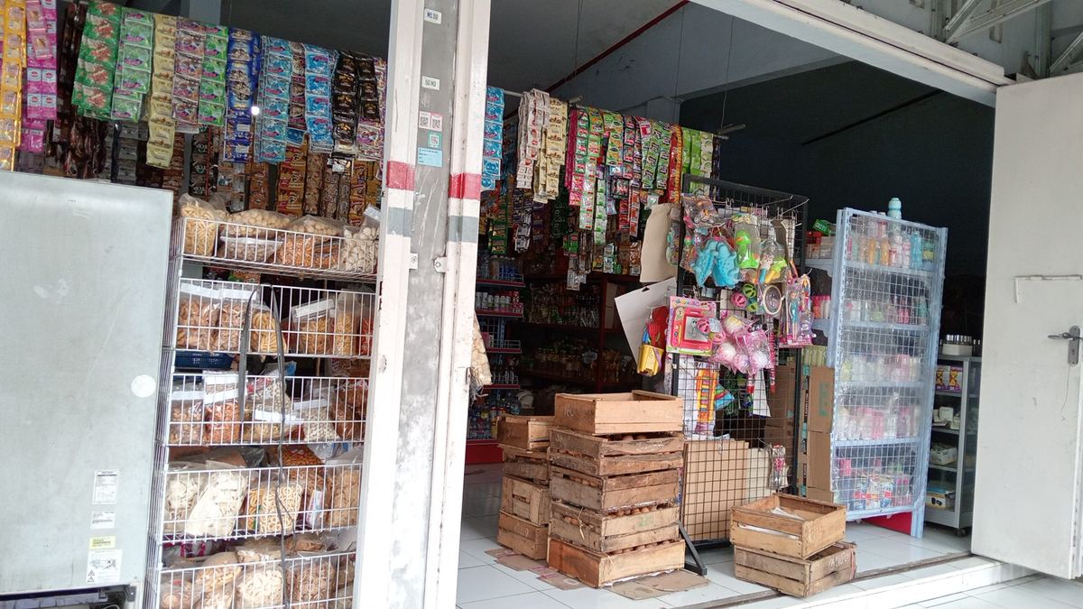 Bagian depan toko dengan rak jajanan dan peti telur kayu